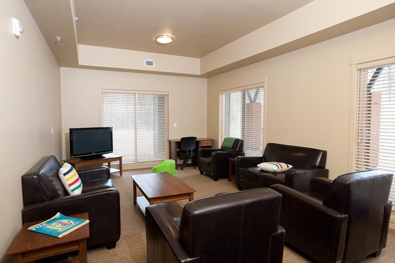 Sitting room filled with tv and leather chairs/couches
