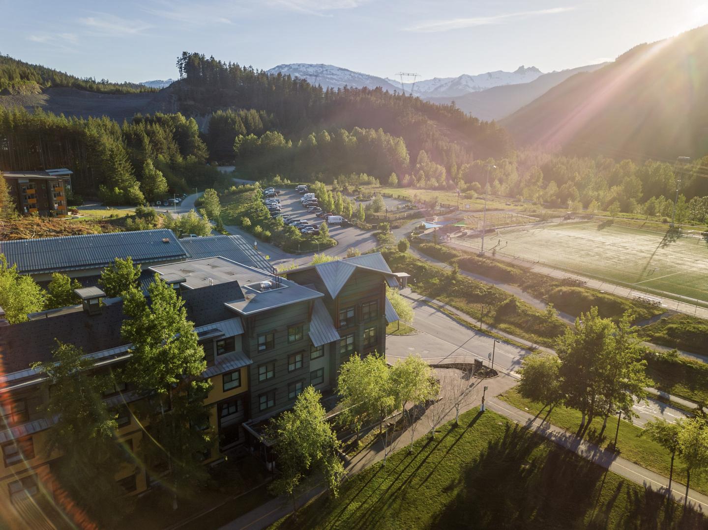 Aerial view of a mountain resort with lush greenery and sunlight.